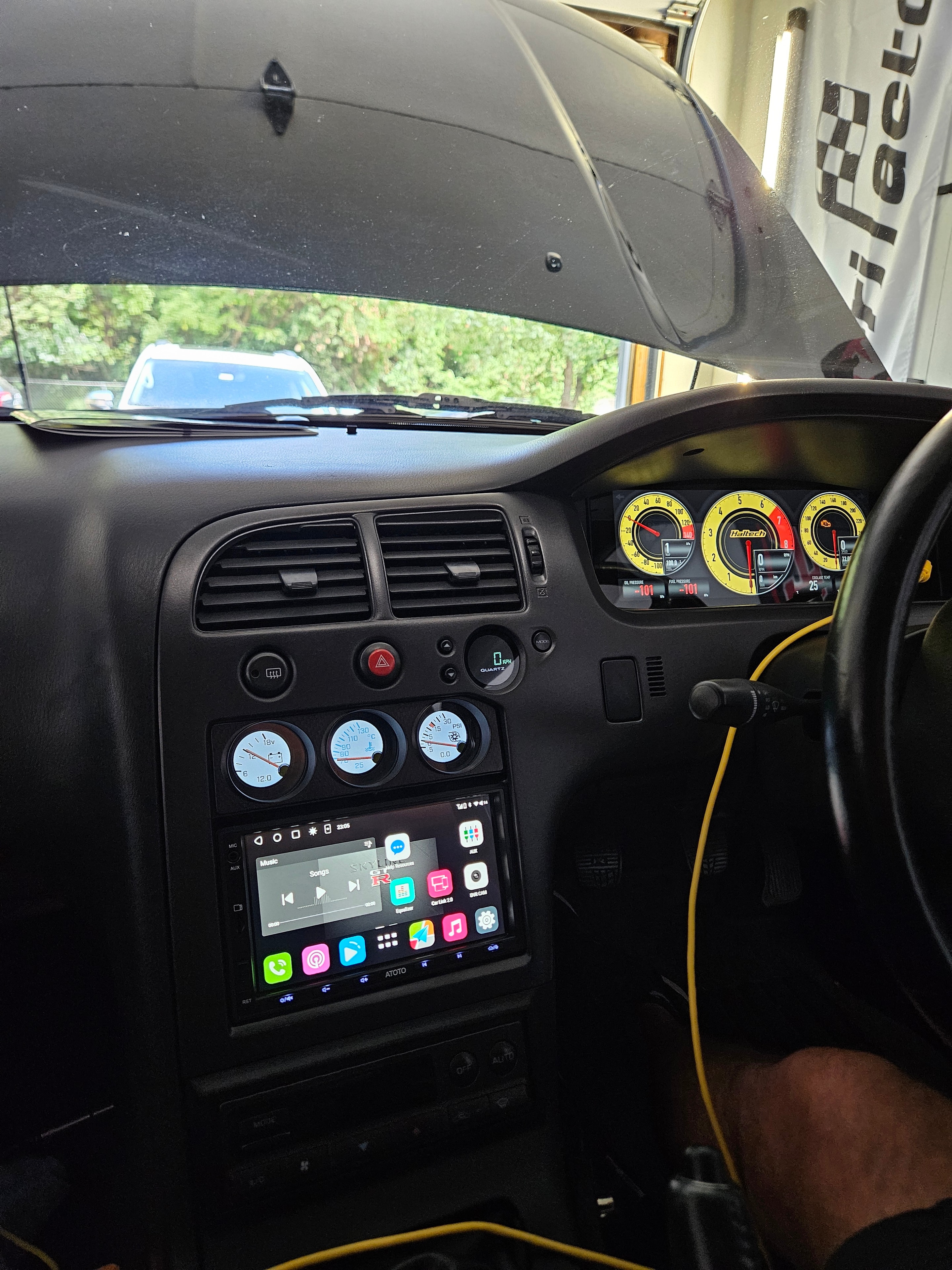 Right-hand-drive BCNR33 cockpit with Haltech display, auxiliary gauges, and center console