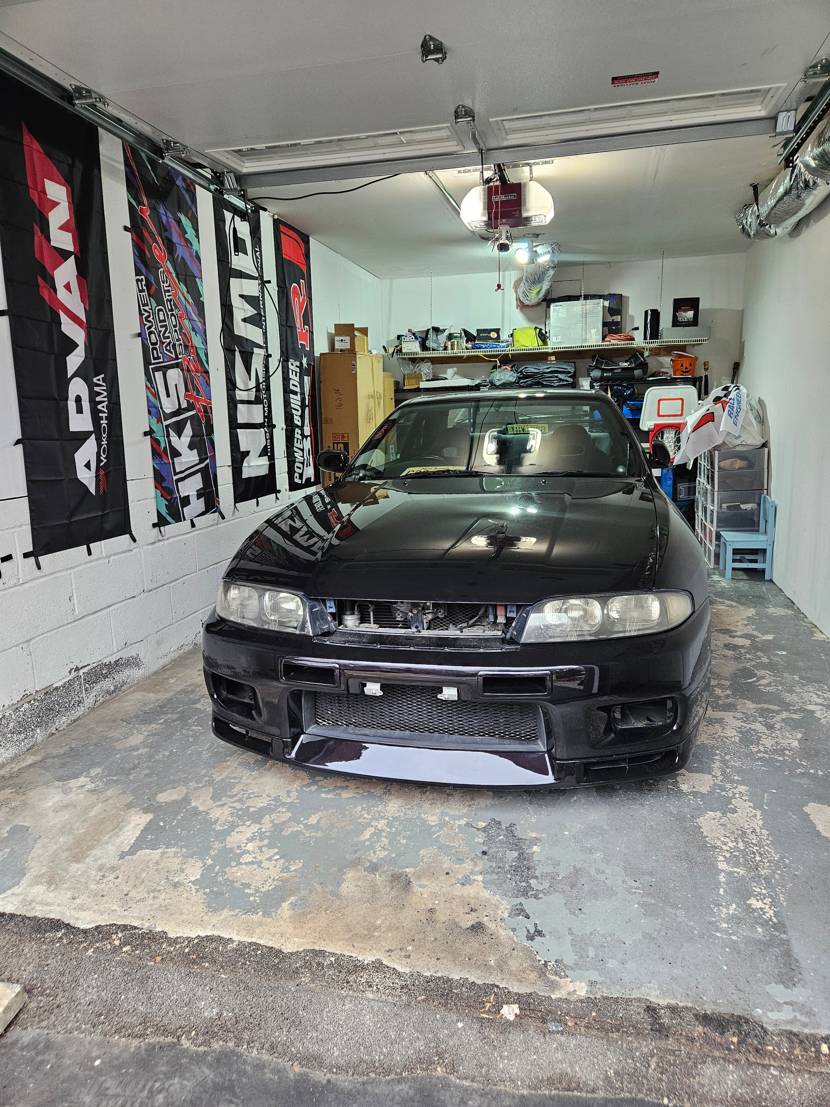 BCNR33 front-end work in progress inside the owner's garage — HKS, Nismo, and Yokohama banners